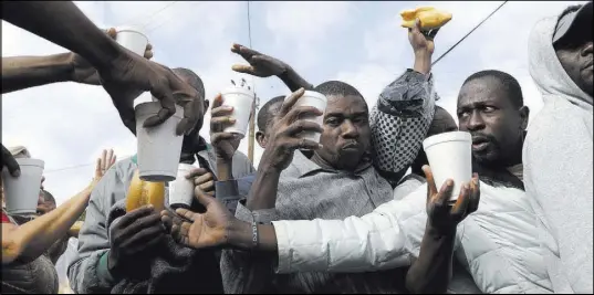  ?? GREGORY BULL/THE ASSOCIATED PRESS ?? Haitian migrants receive food and drinks Monday from volunteers as they wait in line at a Mexican immigratio­n agency in Tijuana with the hope of gaining an appointmen­t to cross to the U.S. side of the border.