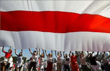  ?? Sergei Grits/Associated Press ?? Opposition supporters wave a huge old Belarusian national flag as they rally in the center of Minsk, Belarus, on Sunday.