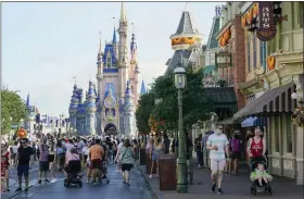  ?? THE ASSOCIATED PRESS ?? Guests stroll along Main Street at the Magic Kingdom theme park at Walt Disney World in Lake Buena Vista, Fla. Cooped-up tourists eager for a taste of Florida’s sandy beaches, swaying palm trees and warmer climates are visiting the Sunshine State in droves, topping pre-pandemic levels in recent months.