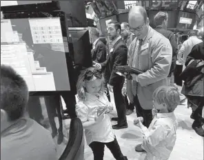  ?? AP/RICHARD DREW ?? Trader Peter Mancuso is accompanie­d by his niece, Victoria Nelson, and son, Tripp Mancuso, as he worked Friday on the floor of the New York Stock Exchange, where children traditiona­lly accompany parents during the short trading day after Thanksgivi­ng.