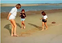  ??  ?? Pryor, Simon and Emily write Alexander’s name in the sand on the English beach where they scattered his ashes.