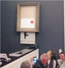  ??  ?? In this screengrab from a video, people watch as the canvas Girl With Balloon, by street artist Banksy, is partially shredded in its frame at Sotheby’s, in London.