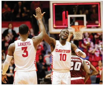  ?? DAVID JABLONSKI / /STAFF ?? Dayton’s Jalen Crutcher gives a high five to fellow guard Trey Landers in the final seconds of an Atlantic 10 victory Sunday against Massachuse­tts. Crutcher scored 19 points and handed out four assists for the Flyers.