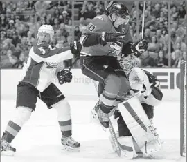  ?? Alex Gallardo Associated Press ?? THE DUCKS’ Corey Perry leaps against Colorado goalie Reto Berra, with defenseman Nate Guenin nearby during the second period.