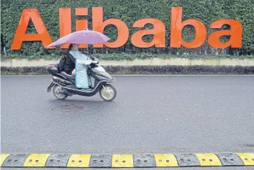  ?? AP ?? A woman rides a bike past the company logo outside the Alibaba Group headquarte­rs in Hangzhou, in eastern China’s Zhejiang province.