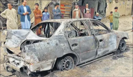 ??  ?? People look at a vehicle that was damaged by a rocket attack in Kabul, Afghanista­n on Monday.