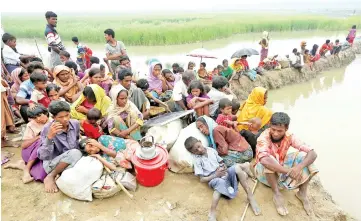  ??  ?? Exhausted Rohingya refugees wait to be taken to a refugee camp after crossing the Naf river at the Bangladesh-Myanmar border in Palong Khali, near Cox’s Bazar, Bangladesh. — Reuters photo