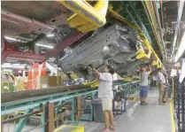  ??  ?? Employees work on the underside of Ford Mustang vehicles on the production line at the Ford Motor Flat Rock Plant in Michigan. — Reuters