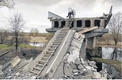  ?? REUTERS ?? A local resident Mykola, 70, climbs down with a stepladder from a bridge destroyed during Russia’s invasion in the village of Kukhari in Kyiv region, Ukraine April 19, 2022.