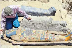  ??  ?? Waking the dead: an Egyptian archaeolog­ist brushes dust from an ancient painted coffin