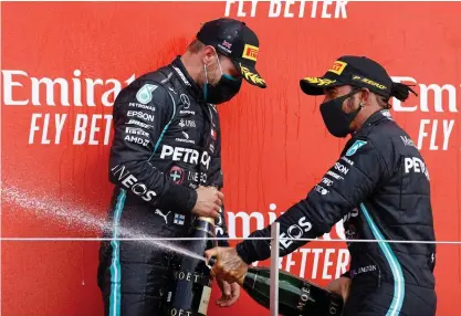  ?? FOTO: AFP / LEHTIKUVA / ANDREW BOYERS ?? Valtteri Bottas (t.v.) ser inte speciellt rodad ut på prispallen då stallkamra­ten Lewis Hamilton sprayar champagne på honom.