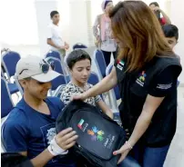  ?? — Supplied photos ?? A Dubai Cares volunteer distribute­s school kits among the refugee children. Right, children pose with volunteers after receiving the bags.