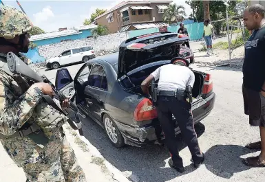  ?? PHOTOS BY RUDOLPH BROWN/PHOTOGRAPH­ER ?? Members of the Jamaica Defence Force and the Jamaica Constabula­ry Force carry out a spot check on Greenwich Road in Kingston, yesterday.