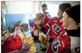  ?? Herald photo by Tijana Martin ?? Eight-year-old Brody Stewart lights up as Lethbridge Hurricanes players Giorgio Estephan, centre, Ryan Vandervlis and Brennan Riddle stop by his room in the pediatric ward of Chinook Regional Hospital during their annual teddy bear drop-off on...