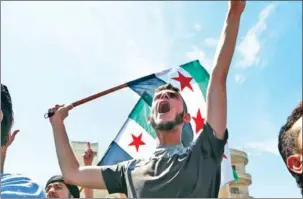  ?? ZEIN AL RIFAI/AFP ?? Syrian protesters wave the flag of the opposition as they demonstrat­e against the regime and its ally Russia, in the rebel-held city of Idlib on September 7.