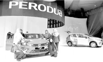  ??  ?? Members of the public pose around a Perodua Myvi on display. MBM is expected to see an increase in its FY19/20 earnings from the launch of the latest Perodua Aruz. — Bernama photo