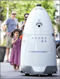  ?? Houston Chronicle/MICHAEL CIAGLO ?? Viola Shaw 4 (left), waves at a new security robot, nicknamed ROD2, as it patrols the sidewalks and parking garage at River Oaks District in Houston earlier this month.