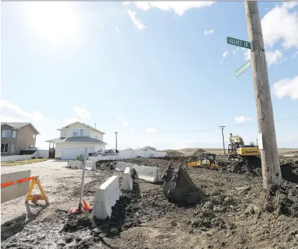  ?? MICHELLE BERG ?? Constructi­on workers service lots for the new Elk Point neighbourh­ood at the corner of 37th Street West and Hughes Drive on Monday. This neighbourh­ood’s official plan, which will be located west of Hampton Village and Dundonald, hasn’t been approved yet.