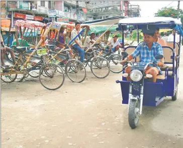  ?? THE KATHMANDU POST ?? An electric rickshaw drives past a line of traditiona­l pedal rickshaws in Nepal.