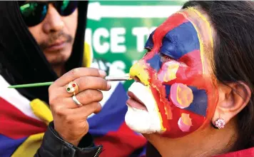  ??  ?? A Tibetan living in exile gets her face painted outside the Dalai Lama’s temple. — AFP photo