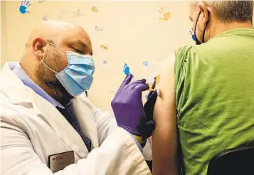  ?? EDUARDO CONTRERAS U-T FILE ?? CVS pharmacist Saif Namiq (left) administer­s a flu shot to Colm Driscoll in El Cajon on Sept. 16. The number of flu cases is increasing with 583 confirmed last week, 34 times the prior five-year average of 17 cases.