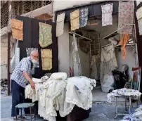  ?? AFP ?? Mohammed Shawash arranges clothes outside his shop in the old city of Aleppo. —