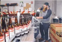  ?? JIM THOMPSON/ JOURNAL ?? Greg Smith adds bottles to the assembly line at Marble Brewery so they can be labeled and filled.