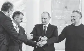  ?? SERGEI ILNITSKY, AP ?? Russia’s Vladimir Putin, center, joins hands with Crimean Premier Sergei Aksyonov, from left, Speaker of Crimean Legislatur­e Vladimir Konstantin­ov and Sevastopol Mayor Alexei Chalyi.