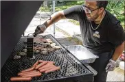  ?? JIM NOELKER / STAFF ?? Malik Hill, owner of Fat Boyz BBQ, cooks up hot dogs and hamburgers at the Juneteenth Celebratio­n at DECA Prep on Homewood Ave.