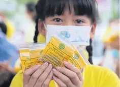  ?? APICHIT JINAKUL ?? A girl shows packs of royally bestowed rice varieties prepared by the Rice Department for attendees of the Royal Ploughing Ceremony.