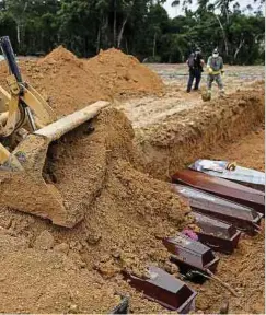  ?? Photo: AFP ?? An excavator covers the coffins buried in a mass grave at the Nossa Senhora cemetary in Manaus, Brazil.