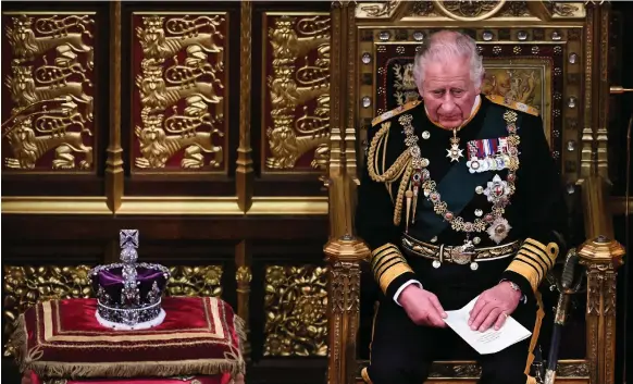  ?? AFP ?? Britain’s Prince Charles holds the queen’s speech as he sits alongside the imperial crown during the State Opening of Parliament in London yesterday