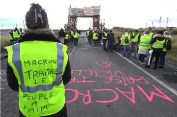  ??  ?? A yellow vests (Gilets jaunes) protester with the words written of the back of her vest that read,‘ Macron (referring to the French President) traitor, the people are hungry’ blocks the road leading to the Frontignan oil depot in the south of France, as they demonstrat­e against the rise in fuel prices and the cost of living.