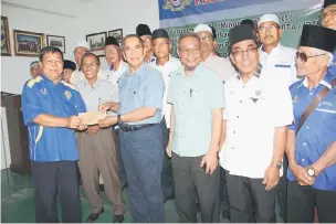  ??  ?? GUNA SEBAIKNYA: Wan Junaidi (empat kanan) menyampaik­an geran MRP kepada salah seorang wakil penerima bagi kawasan Santubong di Kuching, semalam.