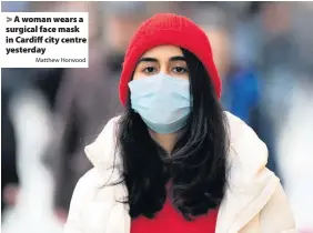  ?? Matthew Horwood ?? > A woman wears a surgical face mask in Cardiff city centre yesterday