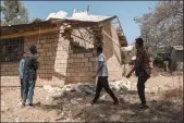  ?? EDUARDO SOTERAS/AFP VIA GETTY IMAGES ?? People stand next to a damaged building at Ksanet Junior Secondary School on March 1. Every phase of the 4-month-old conflict in Tigray has brought suffering to Wukro, a fast-growing transport hub once best-known for its religious and archaeolog­ical sites.