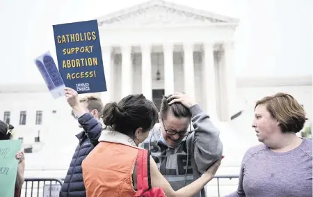  ?? BRENDAN SMIAKOWSKI/AFP TNS ?? Jessica Golibart, center, cries as demonstrat­ors gather in front of the U.S. Supreme Court in Washington on Tuesday. The court is poised to strike down the right to abortion in the U.S., according to a leaked draft of a majority opinion that would shred nearly 50 years of constituti­onal protection­s.