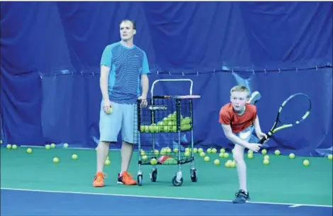  ?? KELSEY LEYVA — THE MORNING JOURNAL ?? Avon Oaks Tennis Center Program Director Brian Dehaven, left, and his 12-year-old son Logan Dehaven watch to see Logan’s serve landed fair while practicing April 12 at the tennis center’s indoor facility, 32300 Detroit Road, in Avon.