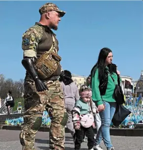  ?? afp ?? Lucky to be home: Kucherenko and Veronika with their youngest daughter, Oleksandra, two, walking past a makeshift memorial for fallen ukrainian soldiers at independen­ce square in Kyiv, ukraine. —