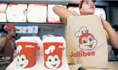  ??  ?? A member of a Jollibee crew packs a take away food for a customer inside a Jollibee franchise in BF Homes Paranaque, Metro Manila. Jollibee Foods Corp, popular in the Philippine­s for its sweet-style spaghetti and fried chicken, is exploring a bid for...