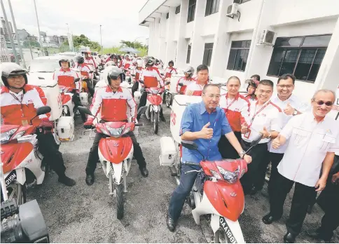  ??  ?? Jailani mounts a postman’s motorbike before flagging off the mail delivery service at Pos Malaysia mail centre in Pending, Kuching.