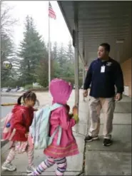  ?? MICHAEL MELIA — THE ASSOCIATED PRESS ?? In this photo, campus monitor Hector Garcia greets students as they got off the bus at the start of the school day at West Elementary School in New Canaan, Conn.