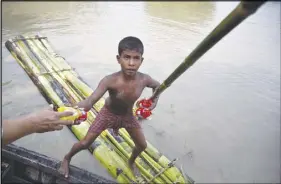  ?? AP PHOTO ?? A flood-affected boy on a makeshift banana raft collects biscuit packets distribute­d by a government official from a boat in Pokoria village, India. Heavy monsoon rains have unleashed landslides and floods that killed dozens of people in recent days...