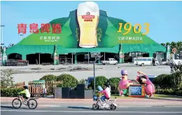  ??  ?? People ride by the Qingdao beer festival.