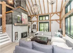  ?? PHOTOS BY WYLIE FORD PHOTOGRAPH­Y ?? The living room has a cathedral ceiling, wooden beams and posts, hardwood flooring, large windows and fireplace with a stone surround and firewood enclave.