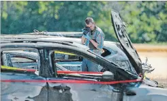  ??  ?? An investigat­or examines the wreckage from Sunday’s fire. Among the losses is a new Tesla.