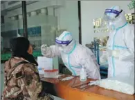  ?? WANG ZHUANGFEI / CHINA DAILY ?? Medical workers collect a sample from a vendor for COVID-19 testing at Qiaoxi market in Shijiazhua­ng, Hebei province, on Monday. The market, which supplies about 85 percent of all the farm products for the city and its surroundin­g areas, is operating normally.