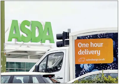  ?? Bloomberg News ?? A Sainsbury’s grocery delivery van passes in front of an Asda supermarke­t last April in Watford, England.