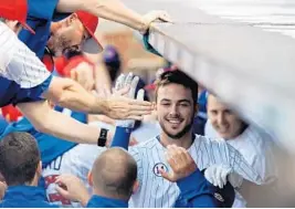  ?? JON DURR/GETTY IMAGES ?? Chicago’s Kris Bryant is congratula­ted in the dugout after hitting a grand slam against the Miami Marlins at Wrigley Field on Saturday. Bryant hit two home runs and finished with six
RBI.