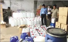  ?? SUPPLIED ?? Authoritie­s inspect containers filled with chemicals used to produce fake toiletries and medicine during a bust on Friday in Phnom Penh.